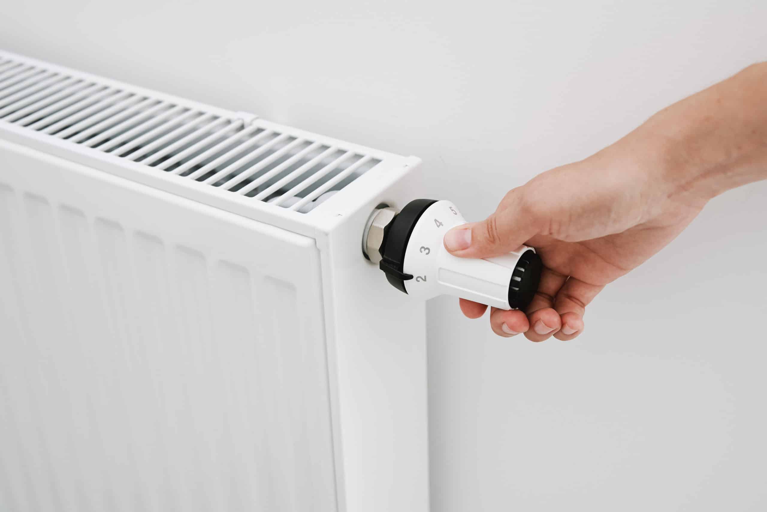 woman hand adjusting temperature on heat radiator